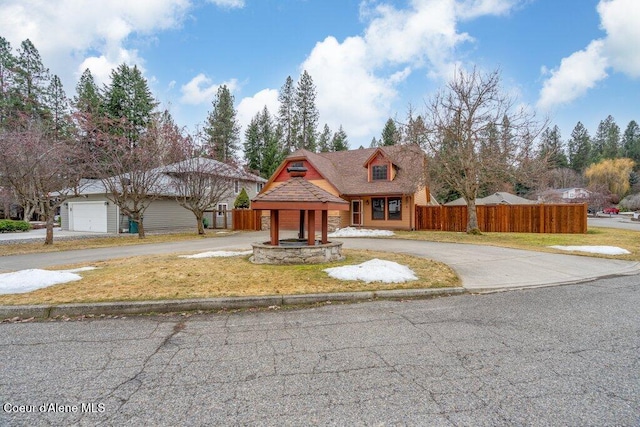 view of front facade with driveway, a front lawn, and fence