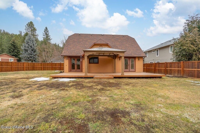 rear view of house featuring a fenced backyard, a deck, and a lawn