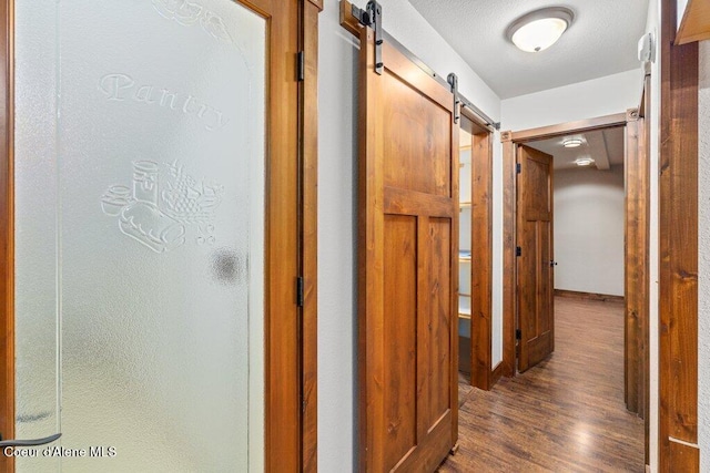 corridor featuring dark wood-style floors and a barn door