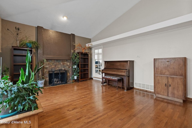 unfurnished living room featuring lofted ceiling, visible vents, a fireplace, and wood finished floors