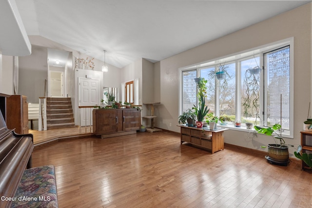 sitting room with lofted ceiling, wood-type flooring, stairs, and baseboards