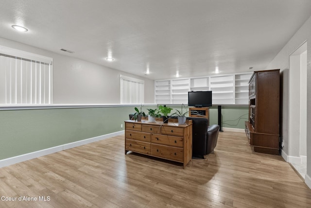 interior space with built in features, wood finished floors, visible vents, and baseboards