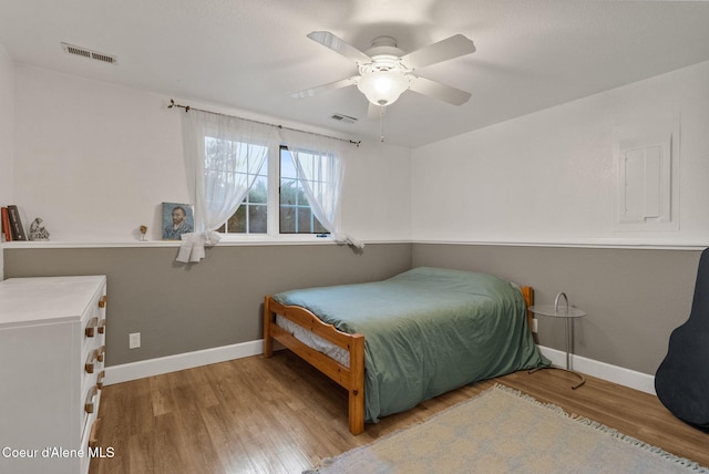 bedroom featuring a ceiling fan, baseboards, visible vents, and wood finished floors