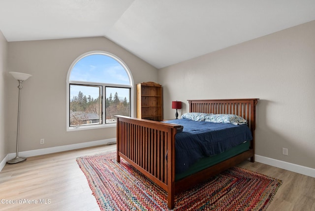 bedroom with vaulted ceiling, light wood-style flooring, and baseboards