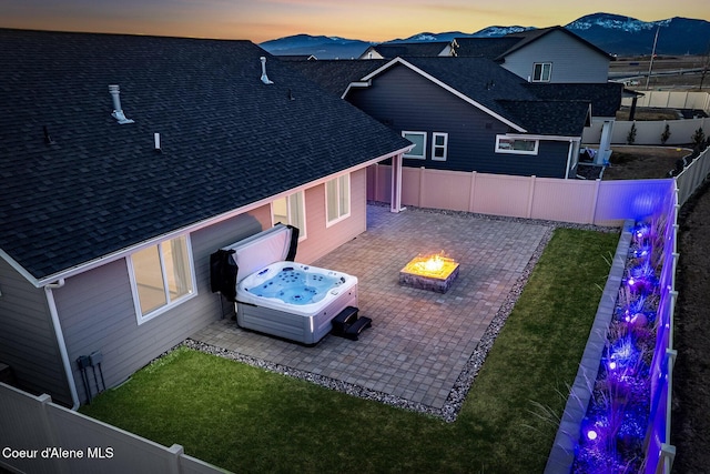 exterior space with a fenced backyard, a mountain view, a fire pit, a patio area, and a hot tub