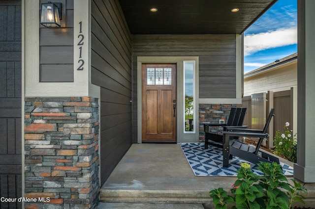 view of exterior entry featuring stone siding and a porch