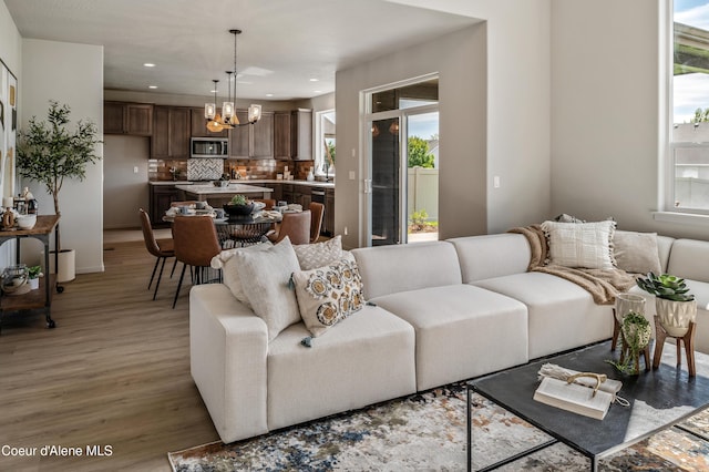 living room featuring recessed lighting, a notable chandelier, and light wood-style flooring