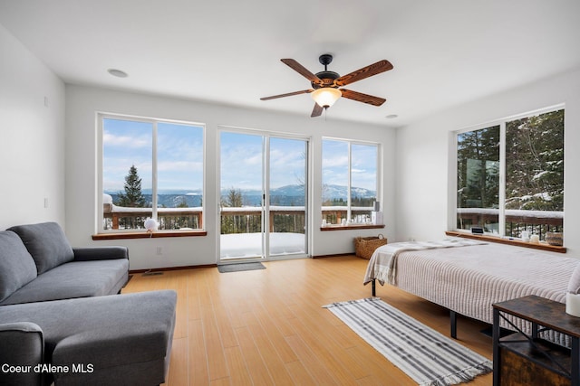 bedroom with a ceiling fan, access to outside, a mountain view, and wood finished floors