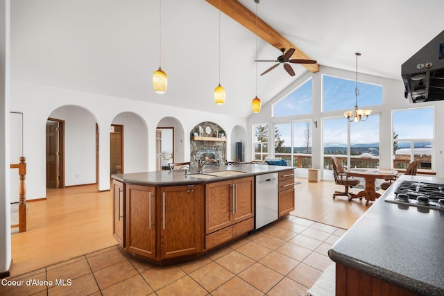 kitchen with dishwashing machine, a sink, brown cabinets, dark countertops, and stainless steel gas stovetop