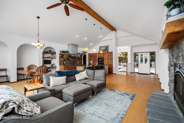 living room with light wood finished floors, a stone fireplace, built in shelves, high vaulted ceiling, and beam ceiling