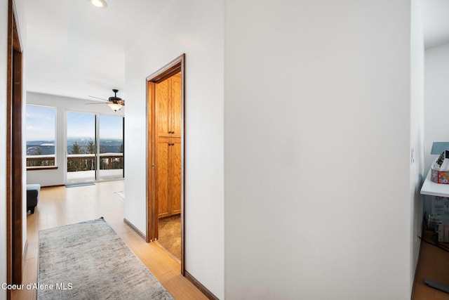 corridor featuring light wood-style floors and baseboards