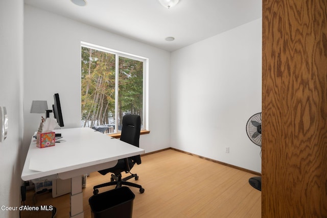 home office with light wood-style flooring and baseboards