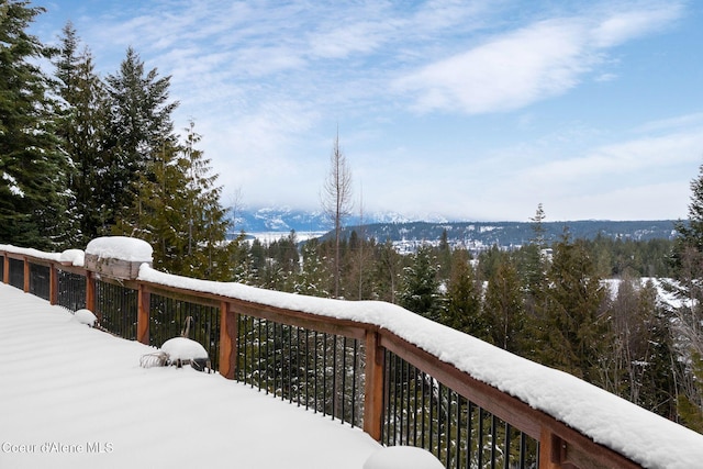 snow covered deck with a view of trees