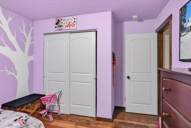 bedroom featuring a textured ceiling, a closet, and dark wood finished floors
