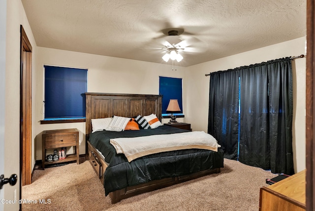 bedroom with ceiling fan, carpet floors, and a textured ceiling