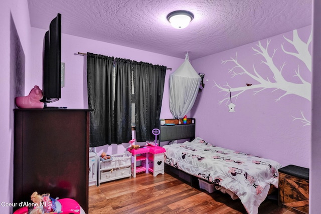 bedroom with wood finished floors and a textured ceiling