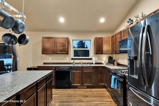 kitchen featuring recessed lighting, black appliances, light wood-style flooring, and a sink