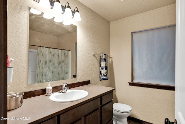 full bath with toilet, vanity, a textured wall, and a shower with shower curtain