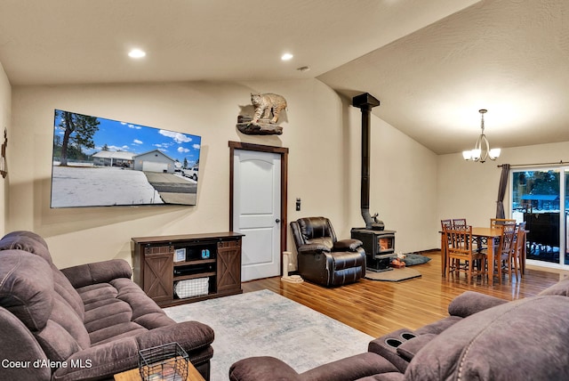 living room with lofted ceiling, recessed lighting, a wood stove, a notable chandelier, and wood finished floors