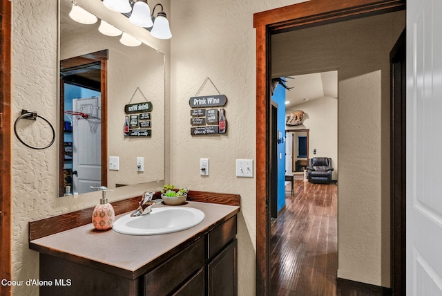 bathroom with a textured wall, vanity, and wood finished floors