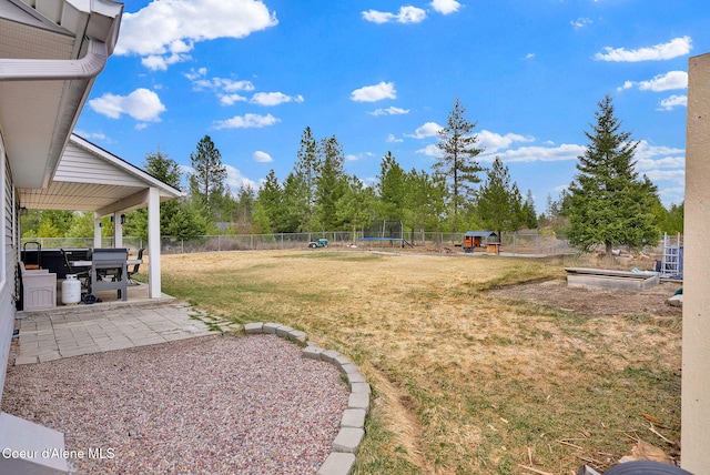 view of yard with a trampoline, a fenced backyard, a vegetable garden, and a patio area