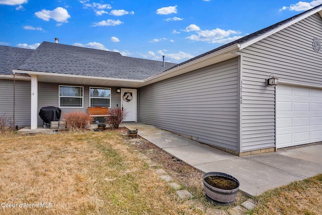 exterior space featuring a lawn, a garage, and roof with shingles