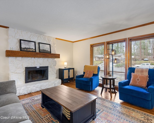 living area with a fireplace, crown molding, and wood finished floors