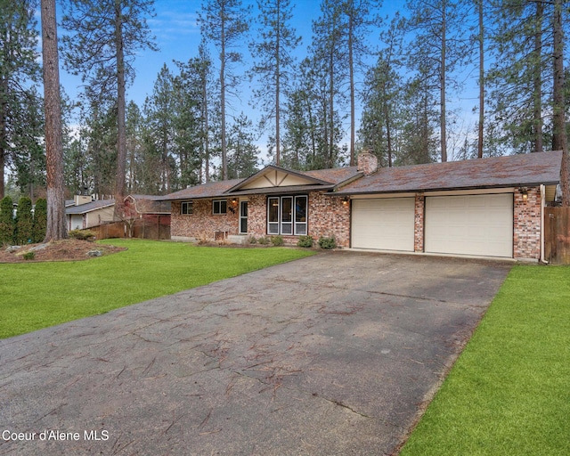 view of front of property with aphalt driveway, brick siding, a chimney, a garage, and a front lawn