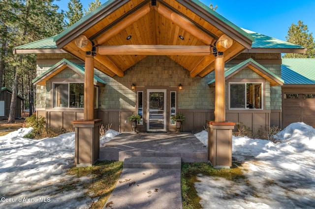 doorway to property featuring a porch and metal roof