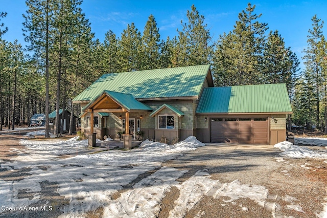 rustic home with a garage, metal roof, and driveway