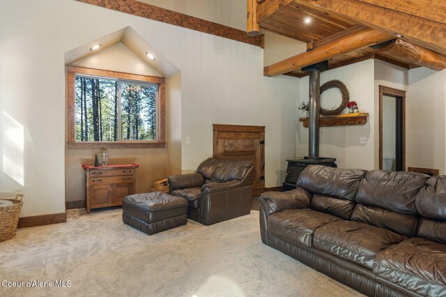 carpeted living area with beamed ceiling, a wood stove, and baseboards