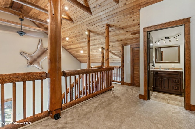 interior space featuring lofted ceiling with beams, wood ceiling, light carpet, a sink, and baseboards