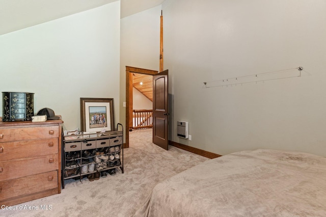 carpeted bedroom featuring heating unit, baseboards, and vaulted ceiling