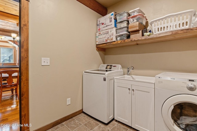 laundry room with washer and dryer, cabinet space, a sink, and baseboards