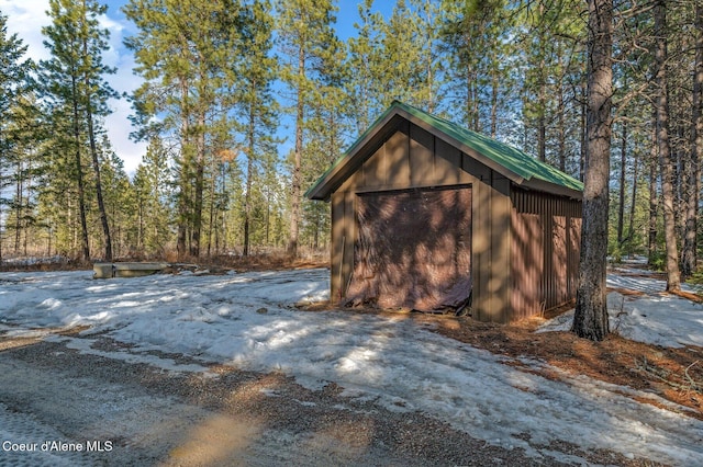 snow covered garage featuring a detached garage and a shed