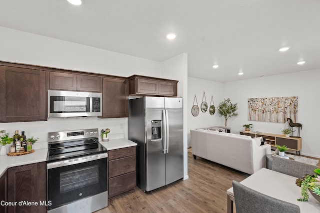 kitchen with light wood finished floors, stainless steel appliances, recessed lighting, light countertops, and dark brown cabinetry