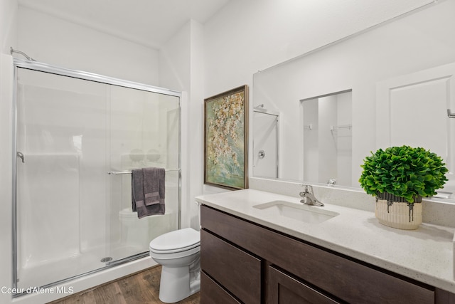 full bath with toilet, a shower stall, wood finished floors, and vanity