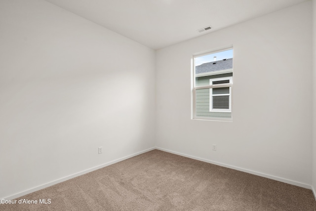 spare room featuring carpet floors, visible vents, and baseboards