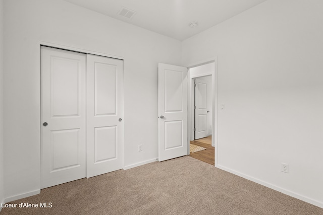 unfurnished bedroom with carpet, a closet, visible vents, and baseboards