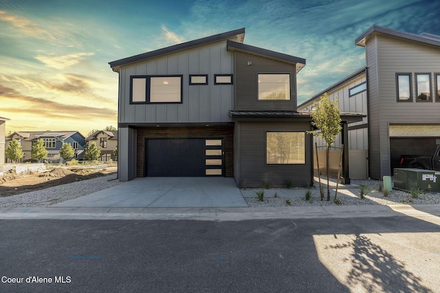 contemporary home with a standing seam roof, metal roof, a garage, concrete driveway, and board and batten siding