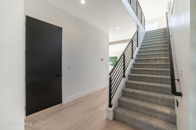 stairway featuring recessed lighting, baseboards, and wood finished floors