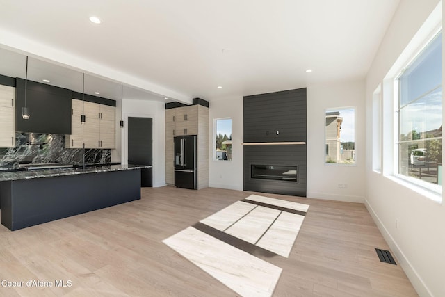 kitchen with high end black refrigerator, a fireplace, visible vents, light wood finished floors, and tasteful backsplash