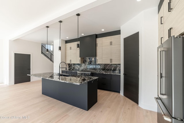 kitchen featuring high end fridge, decorative backsplash, light wood-style floors, a sink, and dark stone counters