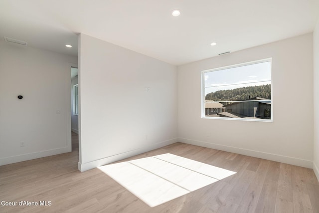 empty room with recessed lighting, wood finished floors, visible vents, and baseboards