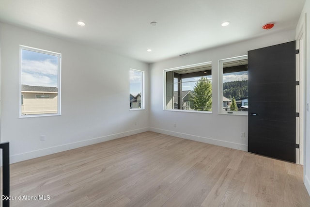 spare room featuring recessed lighting, light wood-style flooring, and baseboards