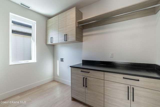 laundry room featuring hookup for a washing machine, visible vents, baseboards, cabinet space, and light wood finished floors