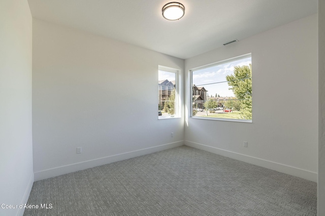 spare room featuring carpet, visible vents, and baseboards