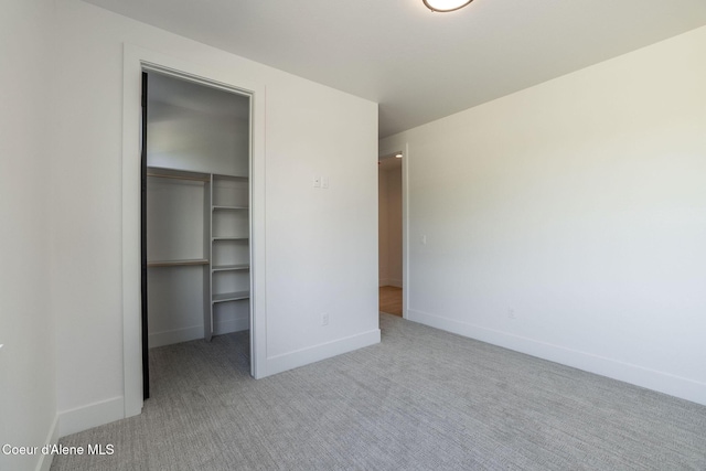 unfurnished bedroom featuring carpet floors, baseboards, a walk in closet, and a closet