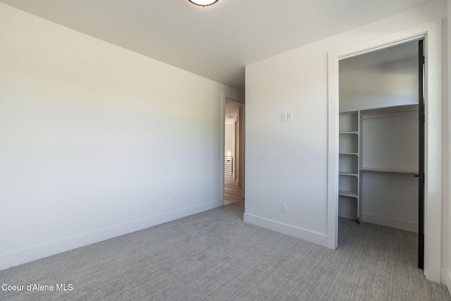 unfurnished bedroom featuring carpet floors, baseboards, a walk in closet, and a closet