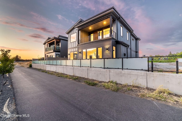 view of front of home with board and batten siding, a balcony, and a fenced front yard